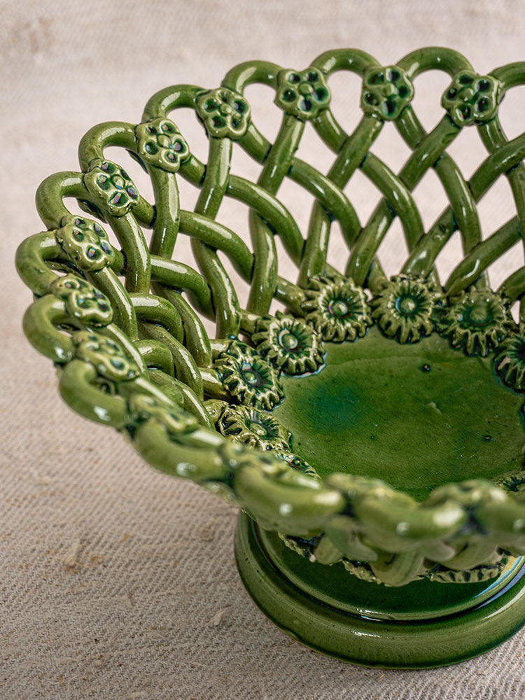 Vintage French Pichon Uzès woven basket with green glaze, mid 20th century, on textured beige fabric background.