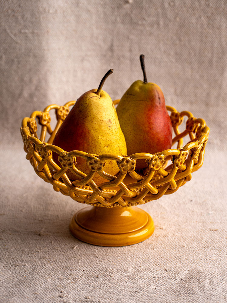Provence Yellow Pichon Uzès woven ceramic bowl with two pears, presented on a pedestal and beige textured fabric backdrop.