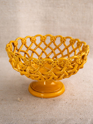 Handmade Provence yellow Pichon Uzès ceramic bowl with lattice and floral detailing, pedestal base, on neutral fabric background.