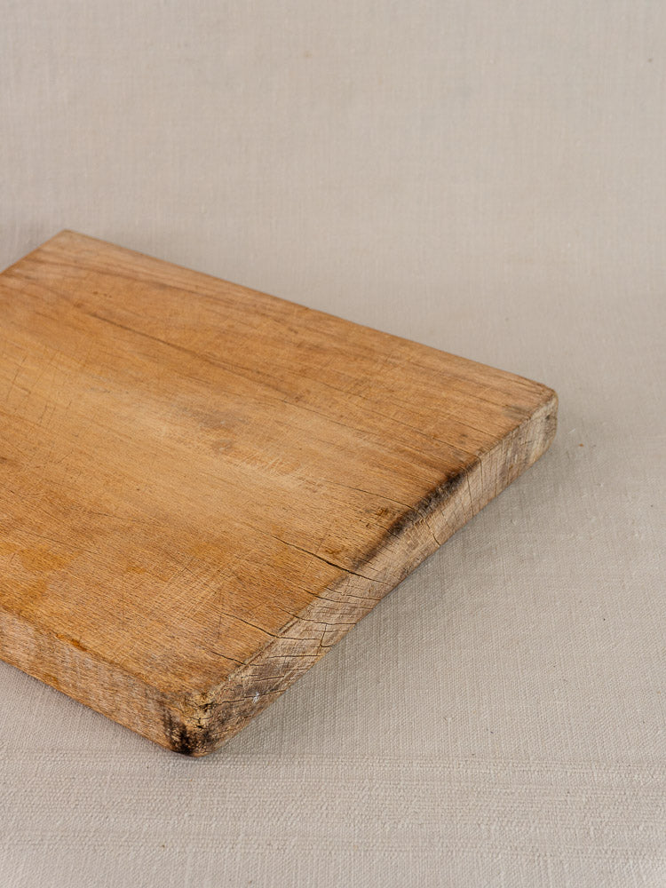 Antique French hardwood cutting board with rectangular worn surface, visible grain, and scratches in Provencal style.