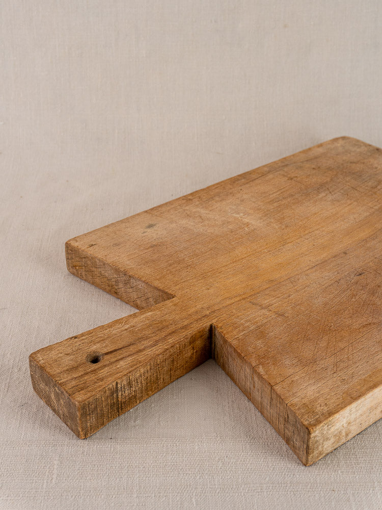 Antique French hardwood cutting board, traditional Provençal style with short handle, hole, grain and knife marks.