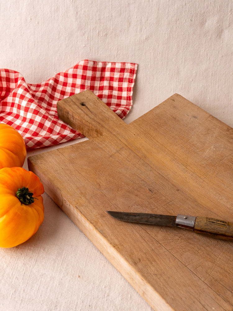 Antique French hardwood cutting board with small knife and yellow tomatoes on a light surface, Provencal kitchen decor.