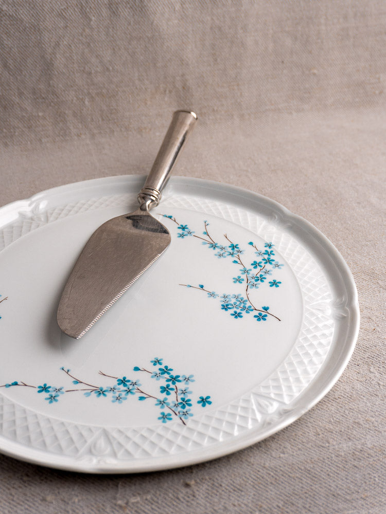 Vintage French Berry Limoges Porcelain cake plate with blue floral design and silver pie server on beige fabric surface.