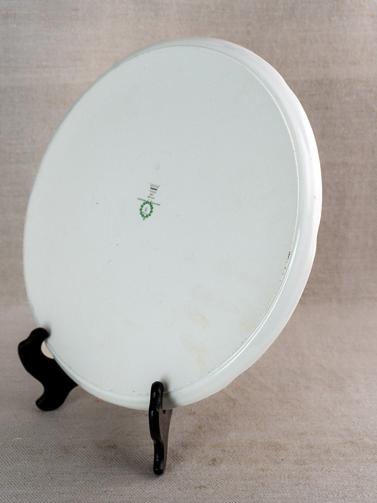 Vintage Berry Limoges French cake plate with blue floral porcelain, green crowned mark, on black stand, neutral background.