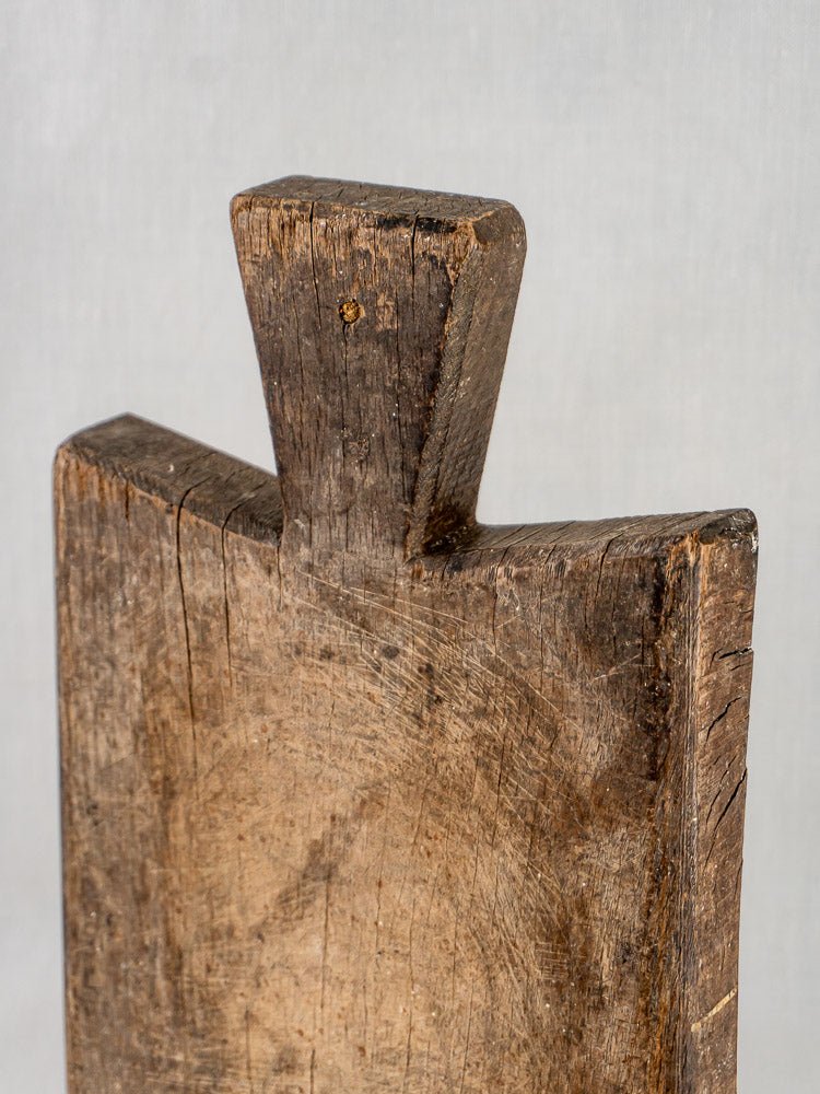 Antique 19th-century French hardwood cutting board with weathered surface and notched handle detail.