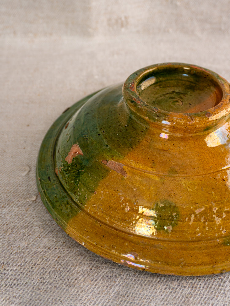 Antique French Provençal compotier with green and ochre glaze, rustic handmade finish, on textured beige fabric.