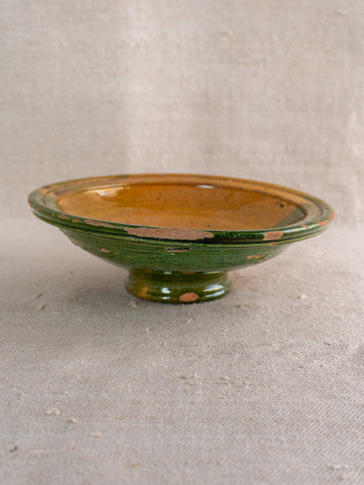Antique French Provençal compotier, late 19th century green and ochre glazed earthenware, displayed on beige textured fabric.