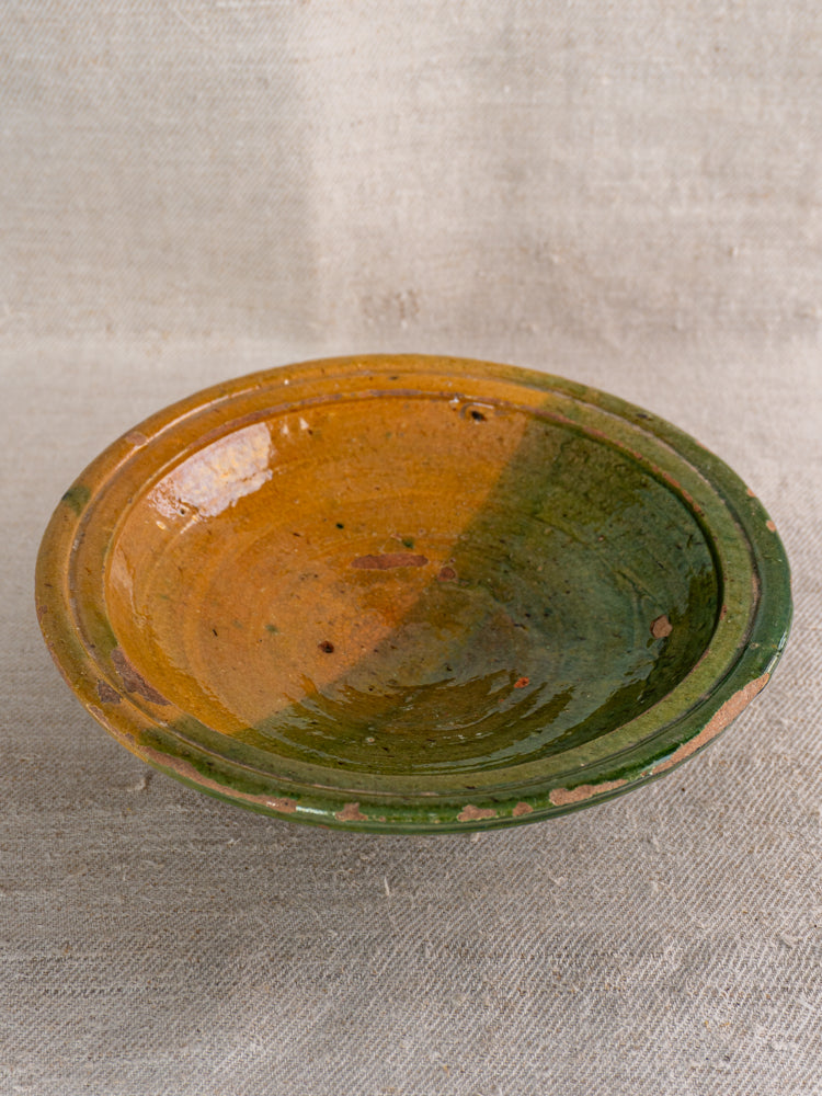 Antique French Provençal compotier, late 19th century, rustic green and ochre glaze, speckled, on beige textured fabric.