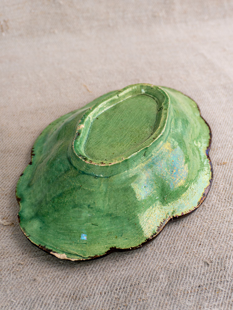 Antique French green glazed oval coupelle, scalloped edges visible, displayed upside down on beige textured fabric.