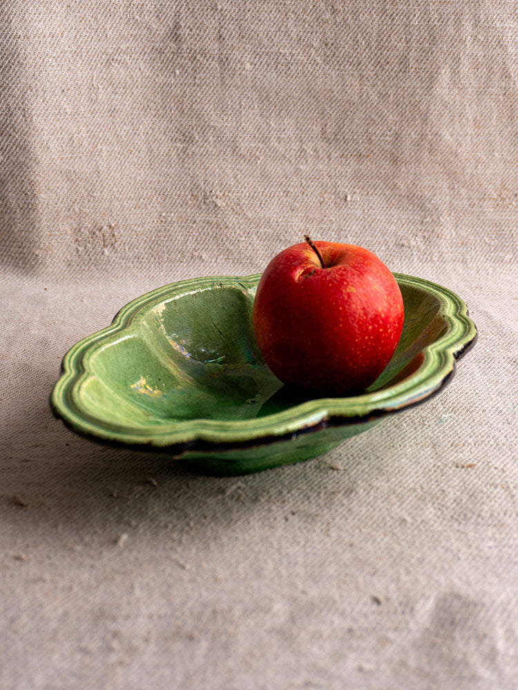 Antique French green glazed lobed oval coupelle from Dieulefit with red apple, on textured beige fabric.