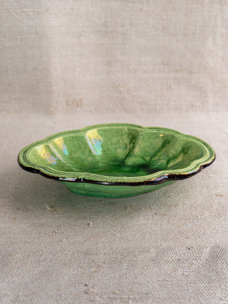 Antique French green glazed oval coupelle with scalloped edge and glossy finish, shown on textured beige fabric.