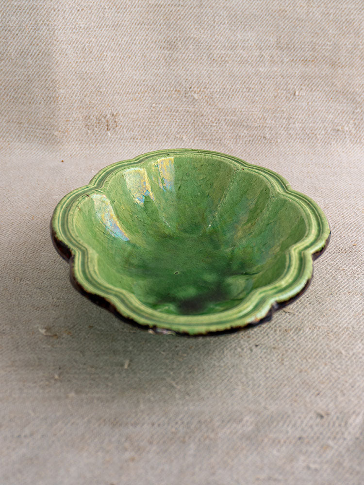 Antique French green glazed lobed oval coupelle with scalloped finish on beige textured fabric.