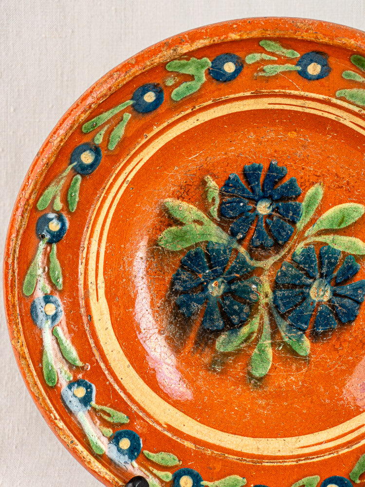 Antique French Alsatian plate, Soufflenheim slipware, with blue flowers and green leaves on an orange ground, c. 1840–1880.