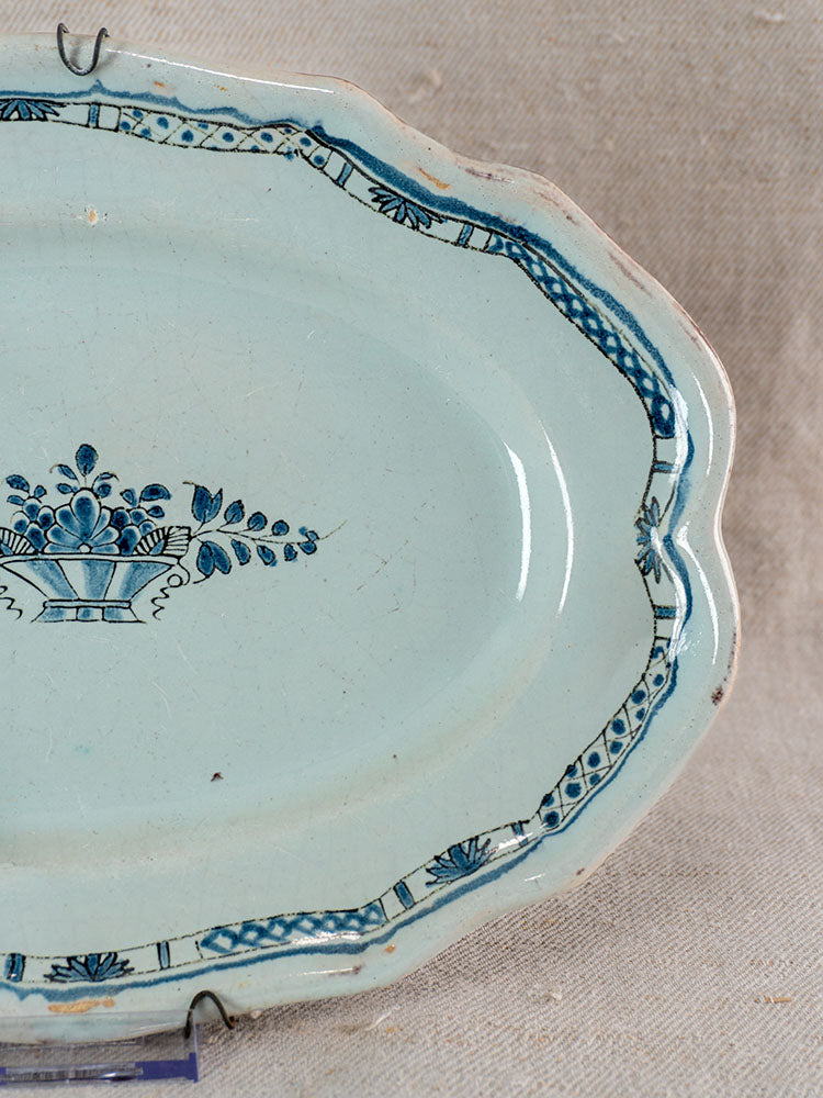 Antique French Rouen faience platter with blue floral basket center, decorative border, and fine surface wear.
