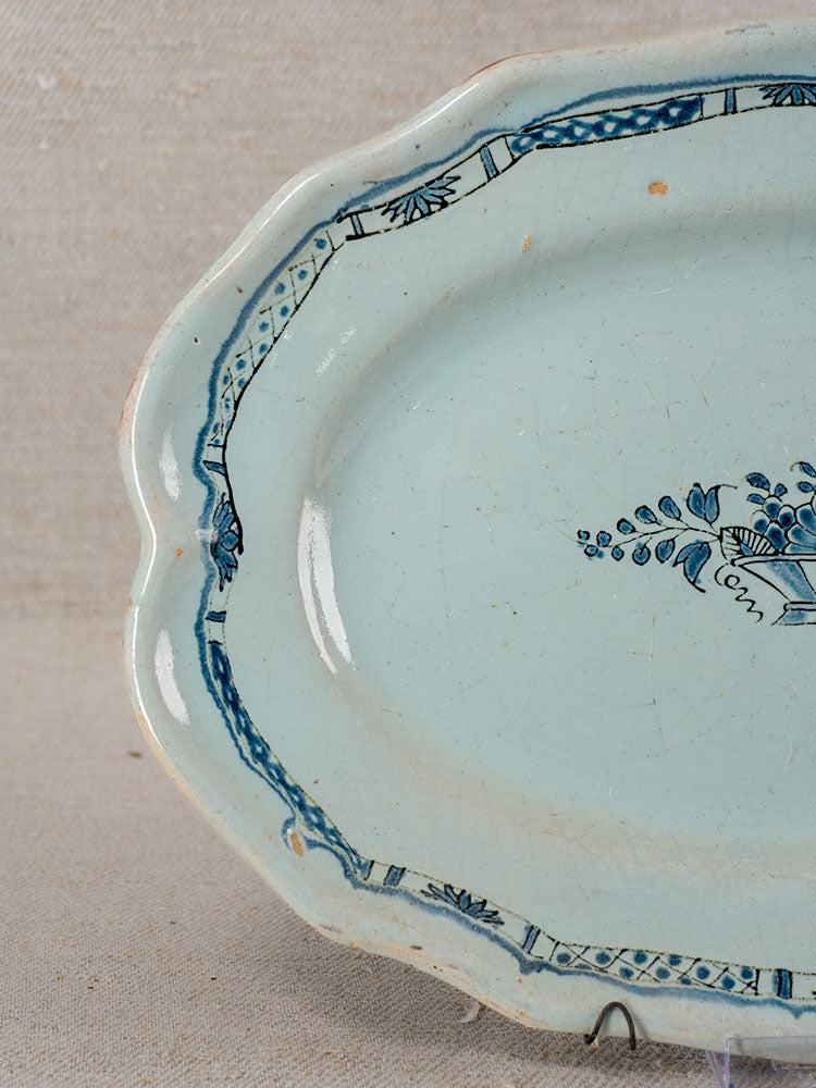 Antique French faience platter, Rouen Tradition Cul Noir, 19th century, blue floral motifs, scalloped edge on neutral fabric.