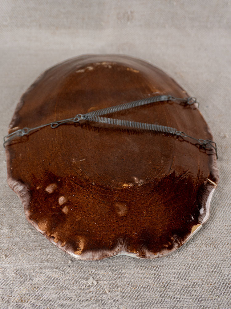 Brown horseshoe crab shell upside down on light surface with two wires, reminiscent of Rouen Tradition faience platter.