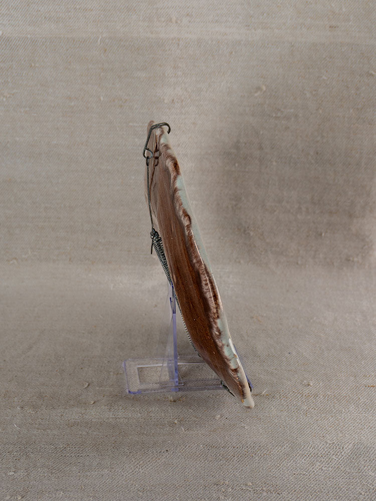 Antique French faience platter, Rouen Cul Noir, 19th century in brown and beige on acrylic stand with fabric backdrop.