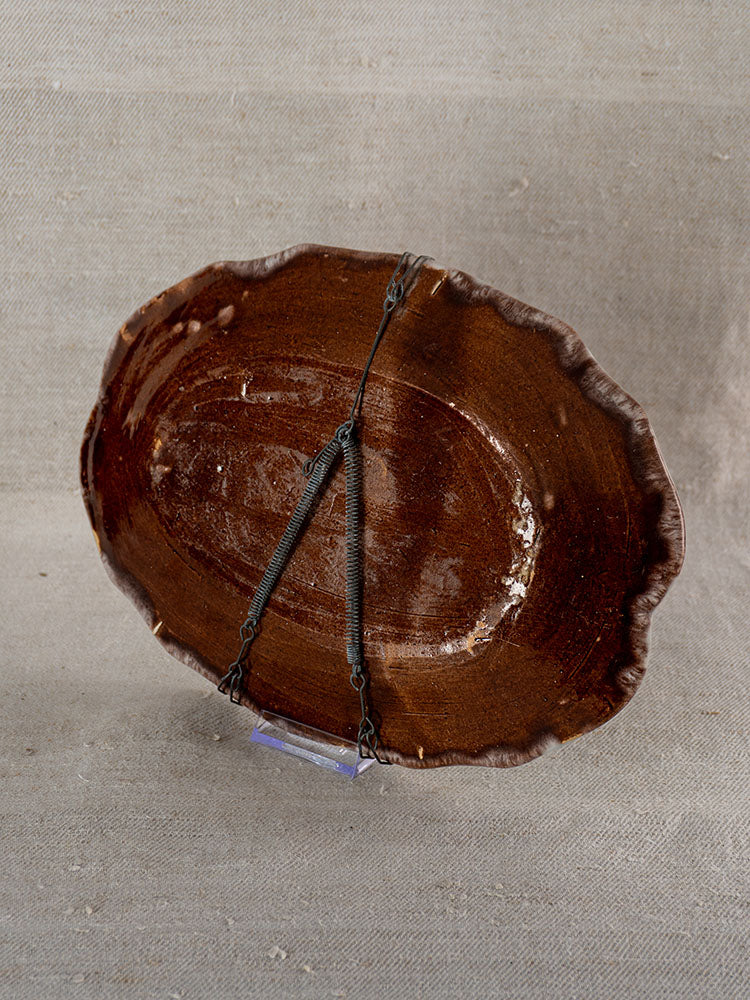 Antique French faience platter, brown oval ceramic with wavy rim, Rouen Tradition, 19th century, on textured fabric.