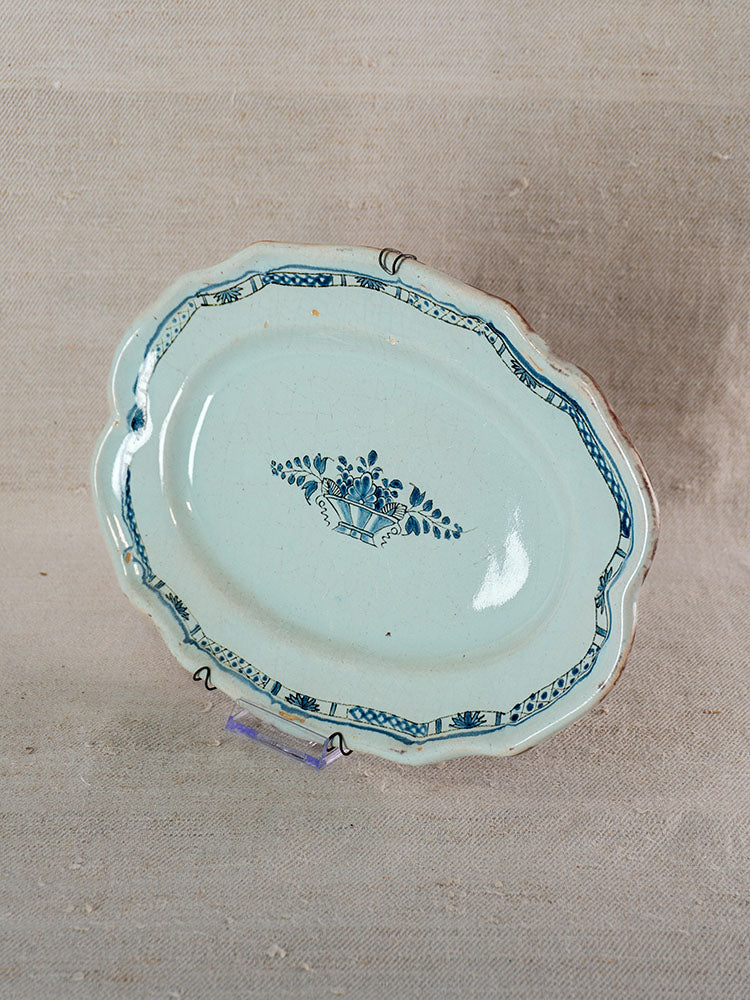 Antique French faience platter with scalloped edge, light blue glaze, and blue floral basket design in Rouen tradition.