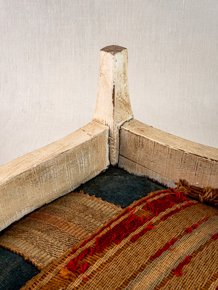 Antique French footstool with worn white-painted Louis XV frame and striped woven hemp seat.