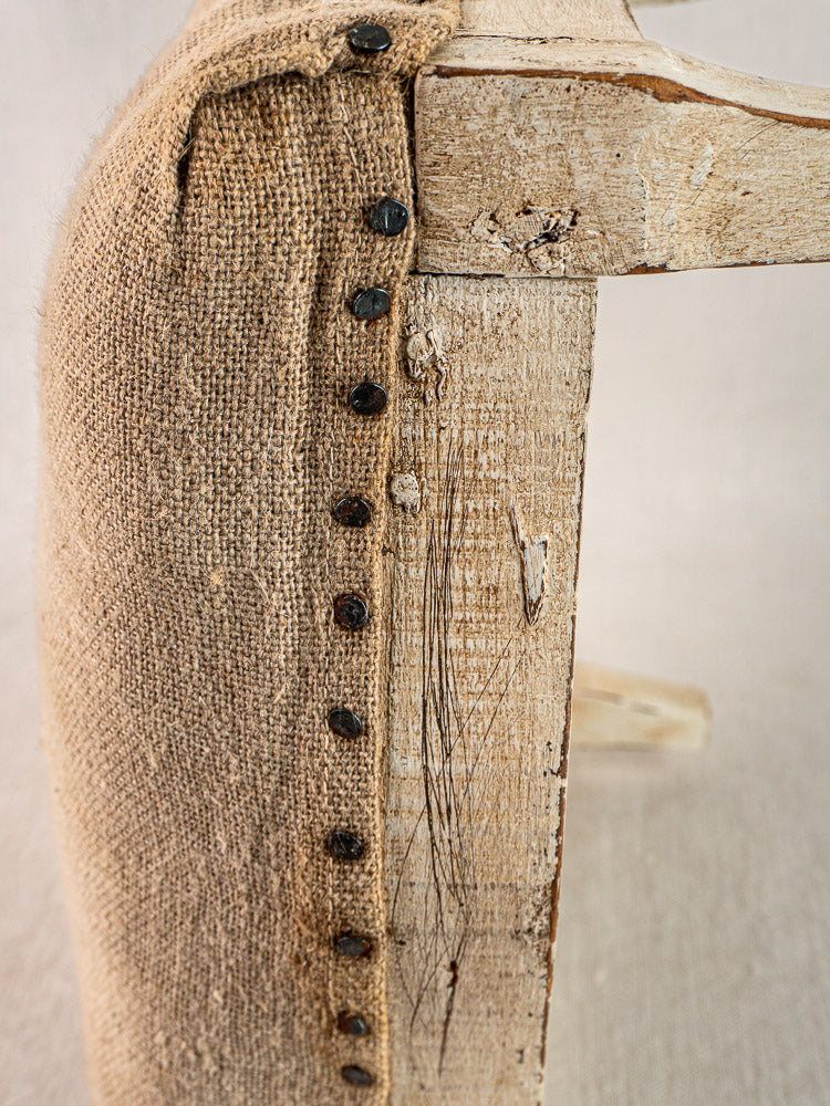 Antique French footstool with painted Louis XV frame, coarse hemp torchon upholstery, and dark metal tacks.