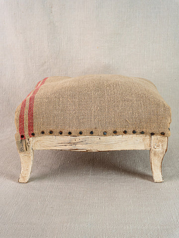 Antique French Louis XV footstool with painted frame, hemp burlap upholstery, red stripes, nailhead trim.