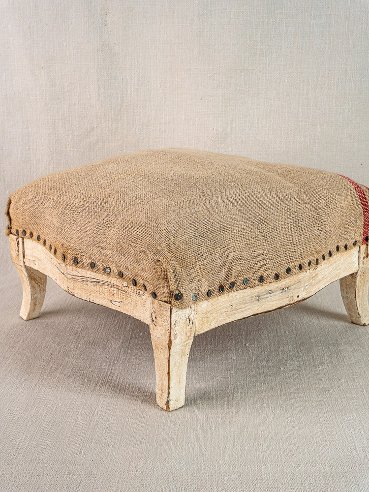 Square ottoman with painted Louis XV frame, hemp torchon upholstery, nailhead trim, distressed wooden legs.