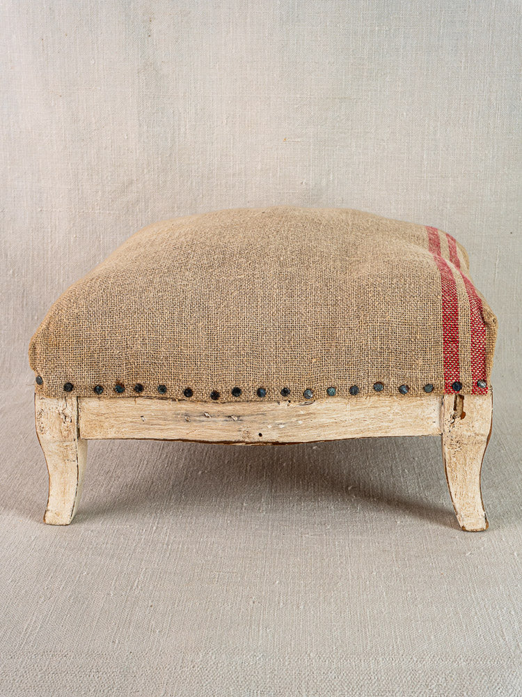 Antique French footstool with painted Louis XV frame, beige and red hemp torchon upholstery, nailhead trim.