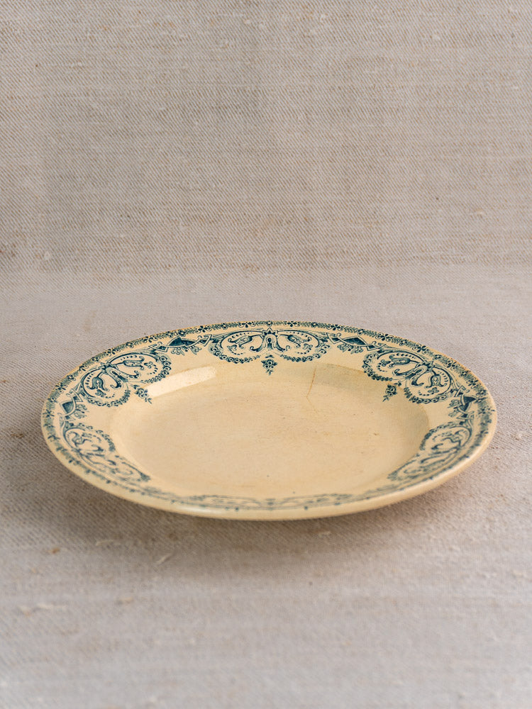 Set of six antique French Terre de Fer faience dinner plates, Caïffa Guirlande green pattern, on neutral textured fabric.