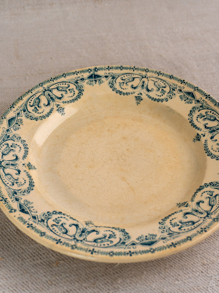 Set of six antique French Terre de Fer faience dinner plates, Caïffa Guirlande blue pattern, on beige textured fabric.