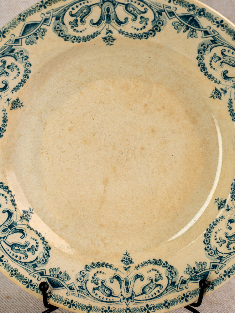 Set of six antique French Terre de Fer faience dinner plates, Caïffa Guirlande pattern, worn beige glaze, ornate blue border.