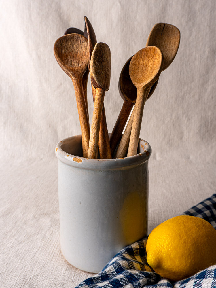 Antique French white-glazed earthenware Pot à Rillettes with wooden spoons, lemon, and checkered cloth.