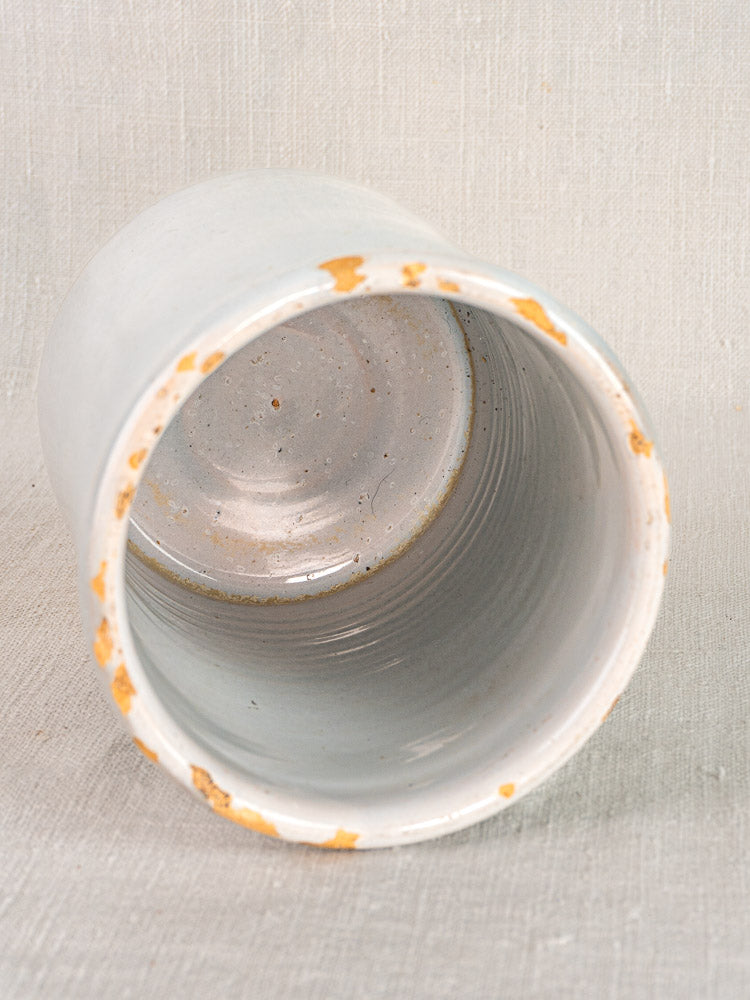 Antique French Pot à Rillettes in white glazed earthenware with worn, chipped rim on textured surface.