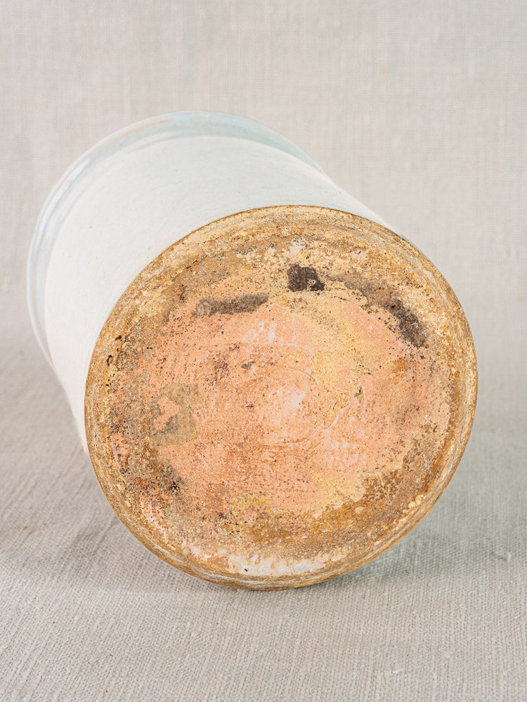 Bottom of antique French white glazed earthenware jar showing rough, weathered surface in earthy tones.