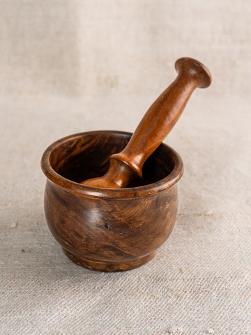 Antique French wooden mortar and pestle, hand-turned with polished wood grain, displayed on textured fabric.