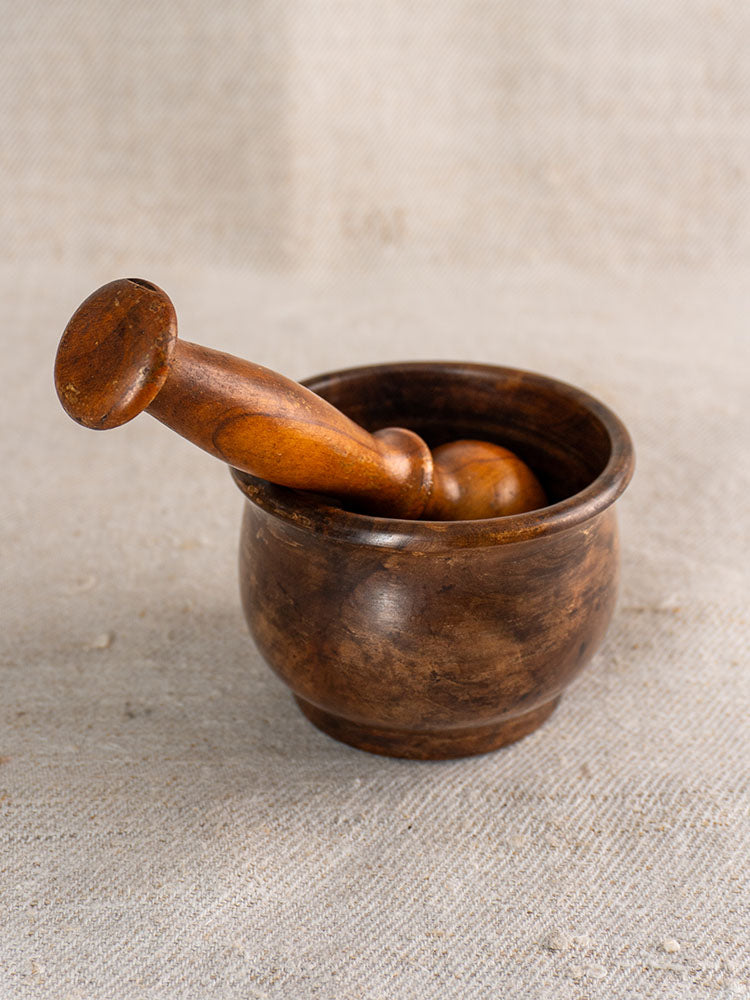 Antique French wooden mortar and pestle, hand turned, displayed on textured beige fabric.