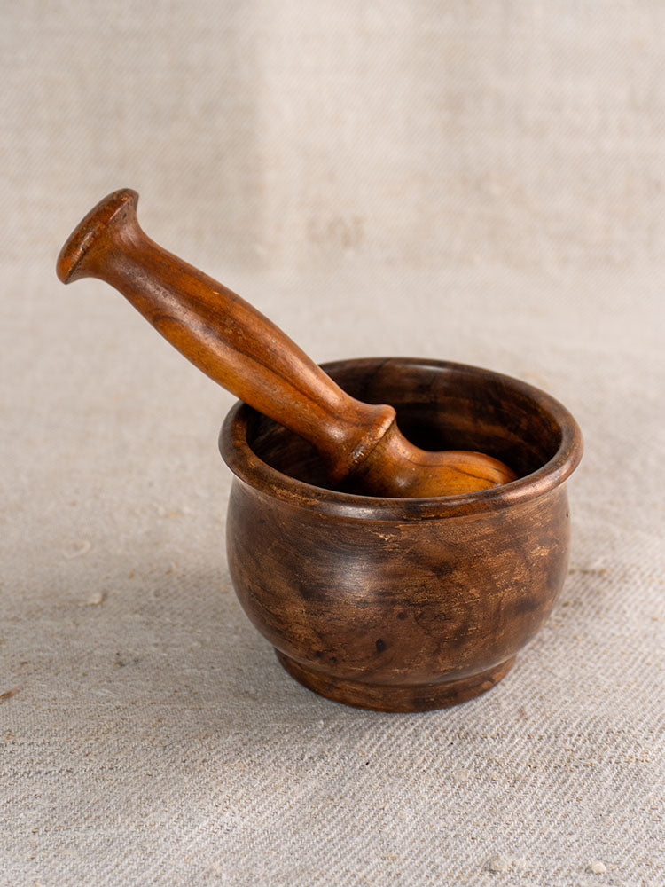 Antique French wooden mortar and pestle, hand turned, displayed on beige textured fabric for vintage kitchen décor.
