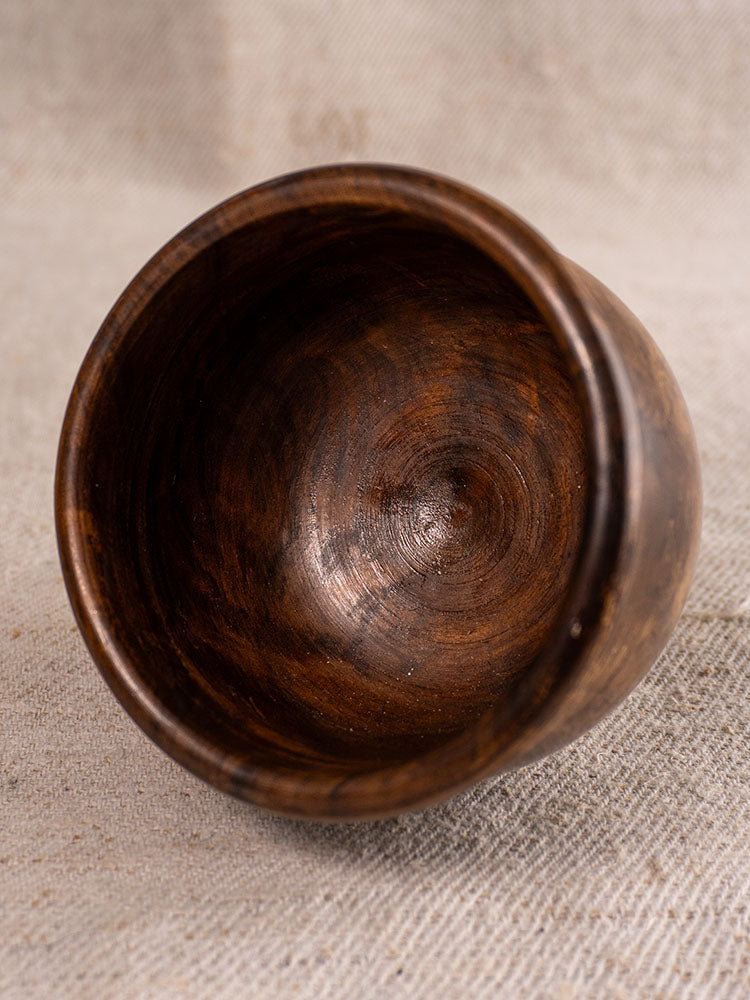Antique French wooden mortar and pestle, 19th century, with smooth dark brown finish on textured beige fabric.