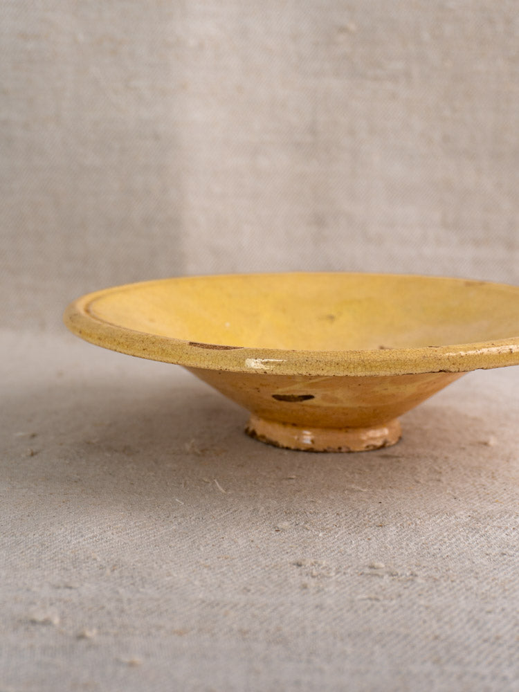 Antique French Tourne Omelette plate, Provencal yellow ochre earthenware, wide rim, on neutral textured fabric.