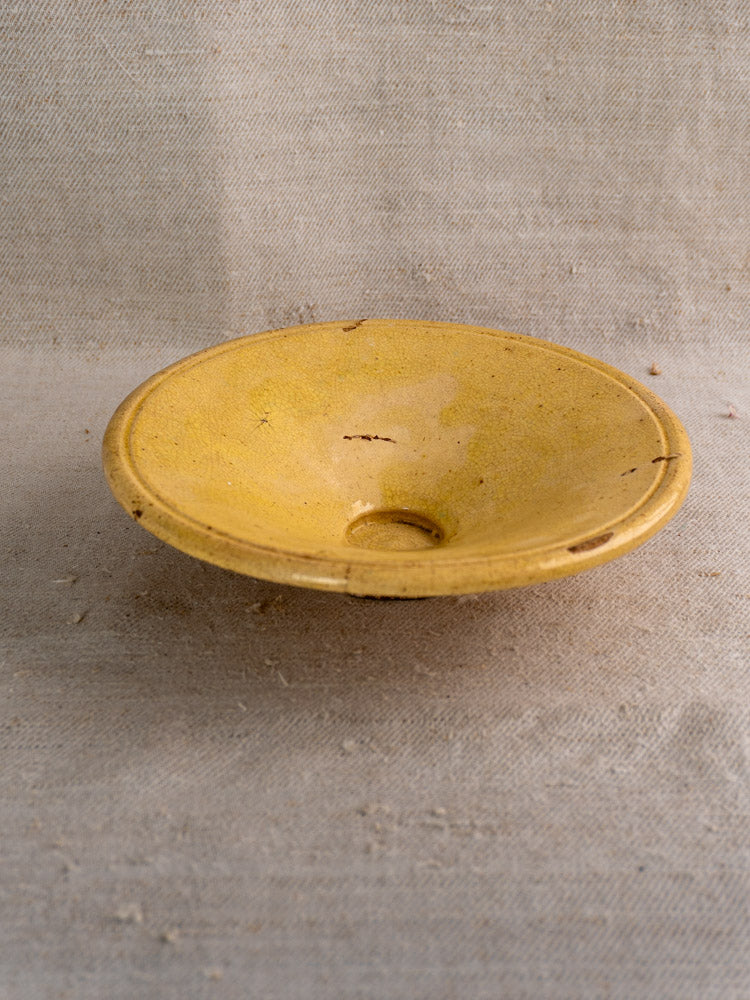 Antique French Tourne Omelette plate, late 19th-century Provençal yellow ochre earthenware on beige textured fabric.