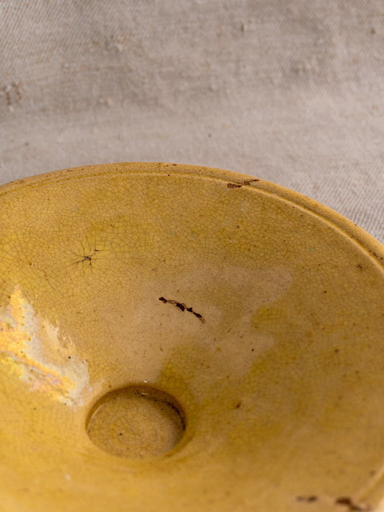 Antique French Tourne Omelette plate, late 19th century Provencal yellow ochre earthenware with visible cracks, on textured surface.
