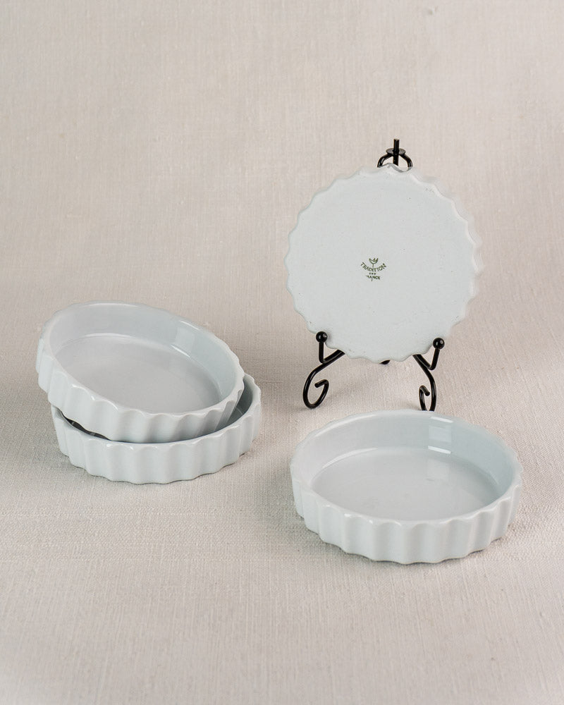 Set of four vintage French CNP quiche dishes with fluted edges, floral logo base displayed.