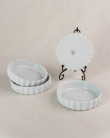 Set of four vintage French CNP quiche dishes with fluted edges, floral logo base displayed.