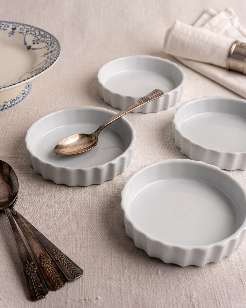 Set of four vintage French CNP quiche dishes with fluted edges, floral logo base displayed.