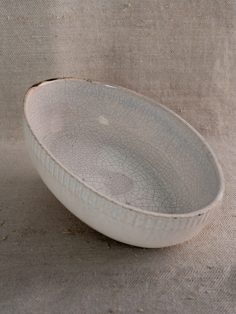Antique French oval earthenware gratin dish, crackled white glaze, brown rim, vertical ridges; early 20th century.