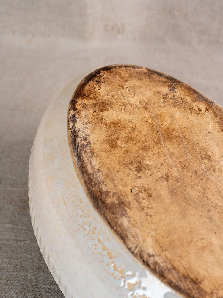 Underside of antique French gratin dish with worn brown base, faint "215 210" stamped on glazed earthenware.