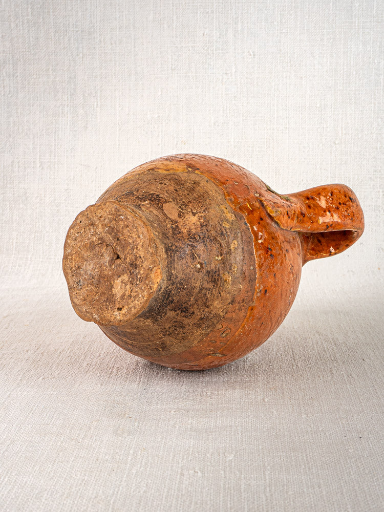 Antique French terracotta wine gourde with rustic orange-brown glaze and two handles on light background.