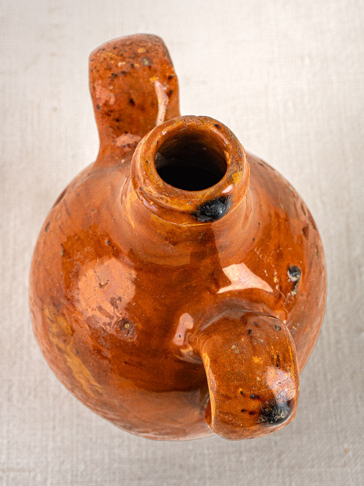 Antique French glazed terracotta two-handled wine gourde with rustic brown ceramic finish on light surface.