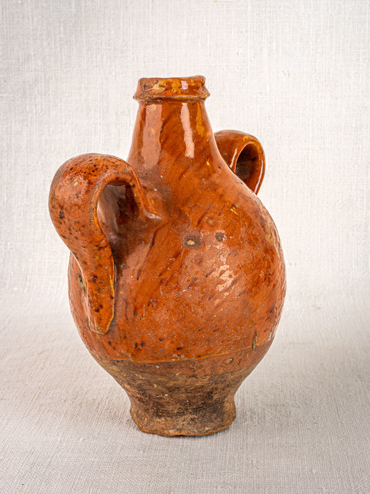 Antique French terracotta wine gourde with two curved handles, glossy brown finish, earthy worn base.