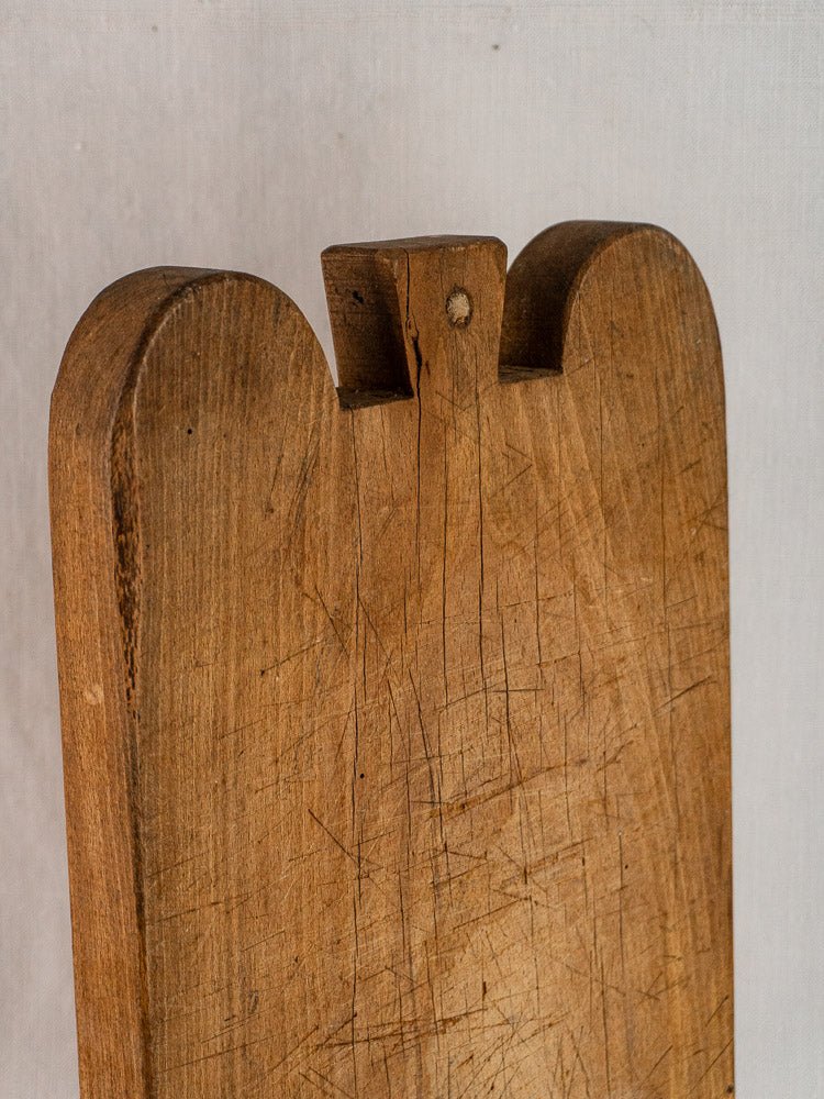 Antique French double-lobed hardwood cutting board with rounded edges, top groove, and visible knife marks.